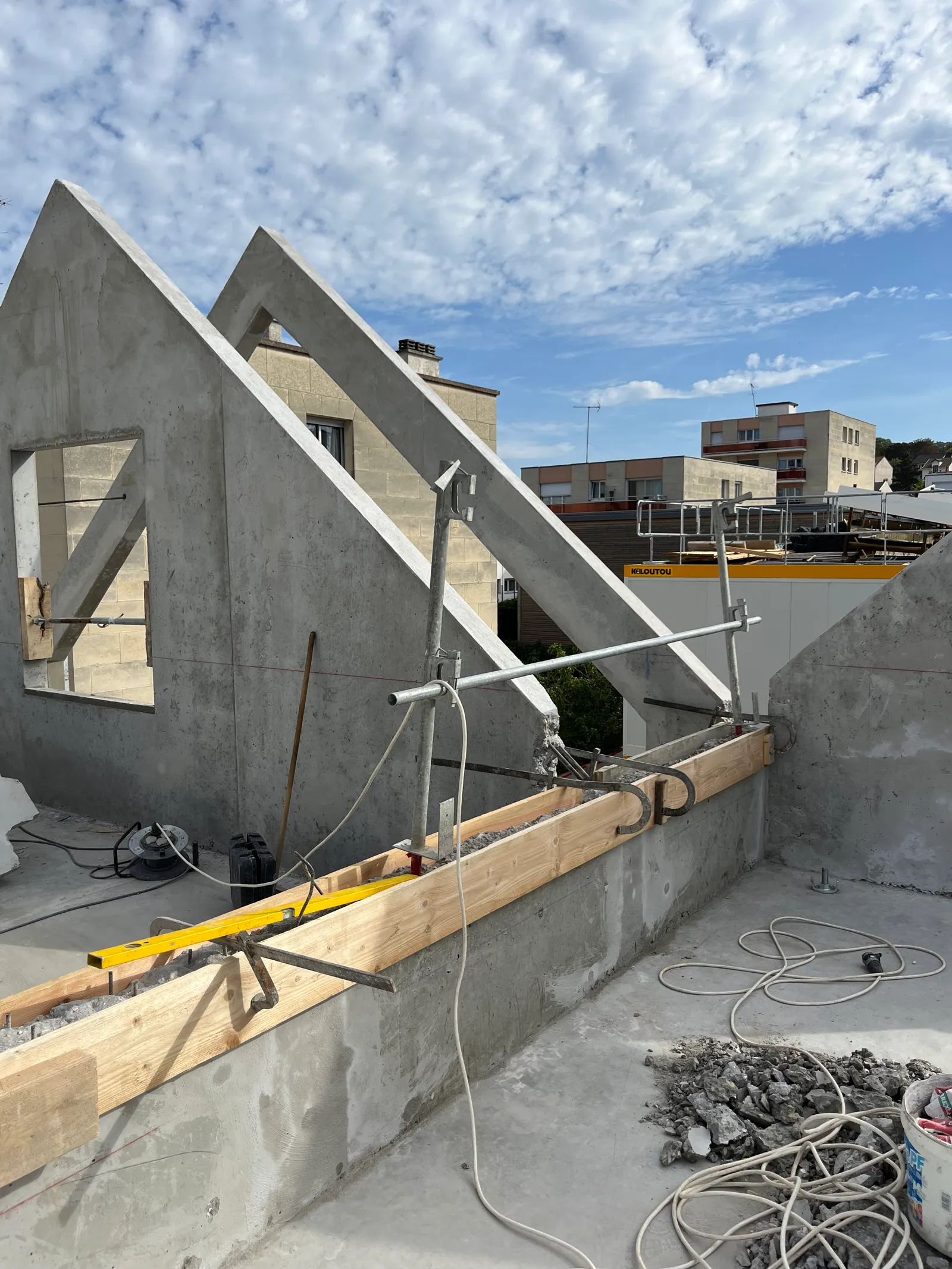 Les pignons en béton banché en cours de réalisation, étais tirants-poussants et lisse de coffrage en attente sur l'acrotère.